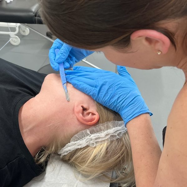A student practicing blade handling techniques during a professional dermaplaning course training session